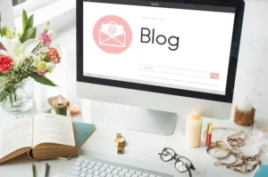 A computer monitor displaying a blog, with a flower vase, books, accessories, and a candle in front – representing a cozy workspace for content creation by content marketing services in Dubai