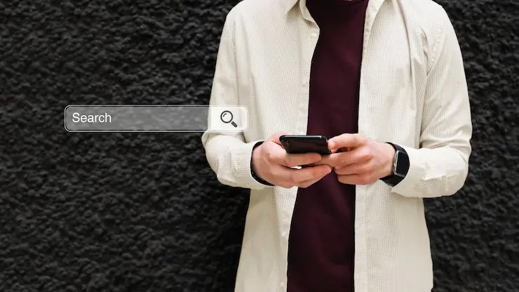 A man searches for information on a mobile phone representing on the go keyword research and mobile optimization strategies for SEO Dubai UAE